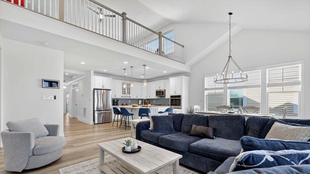 A spacious living area with a sofa, a coffee table, and a grey armchair. - Arbor-Lyn * 4BR Luxury House, Sleeps 10 (Rehoboth Beach)