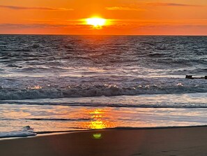 A sunset over the ocean with waves reflecting the sun's light. - Arbor-Lyn * 4BR Luxury House, Sleeps 10 (Rehoboth Beach)
