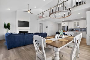 A modern living room with a sofa, dining table, chairs, and a fireplace.