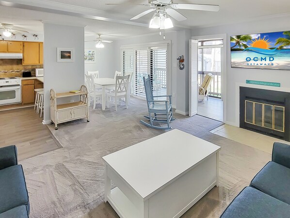 Uma sala de estar moderna com um sofá branco, uma mesa de jantar e uma cozinha com armários de madeira.