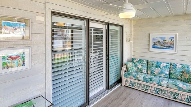 A room with a sliding glass door, a sofa with a tropical print, and framed artwork on the walls. - 2 Blocks from the Beach and Ocean! Updated 2 bedroom Condo with Pool! Our Place at the Beach #H107 (Ocean City)