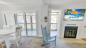 A room with a dining table, chairs, a rocking chair, a fireplace, and a view of the outdoors through a sliding glass door. - 2 Blocks from the Beach and Ocean! Updated 2 bedroom Condo with Pool! Our Place at the Beach #H107 (Ocean City)