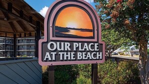 A sign with the text "OUR PLACE AT THE BEACH" and a sunset view. - 2 Blocks from the Beach and Ocean! Updated 2 bedroom Condo with Pool! Our Place at the Beach #H107 (Ocean City)