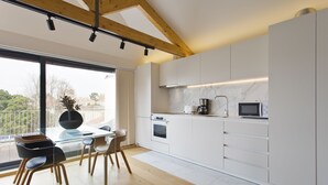 A modern kitchen with white cabinets, a glass dining table, and wooden chairs.