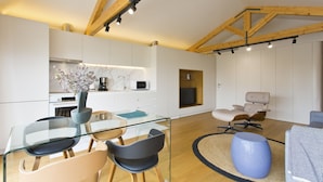 A modern interior with a glass dining table, chairs, a sofa, and a large blue vase.