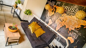 A modern living area with a dark grey sofa, a wooden side table with a potted plant, and a world map mural on the wall. - De Requka (Pereira)