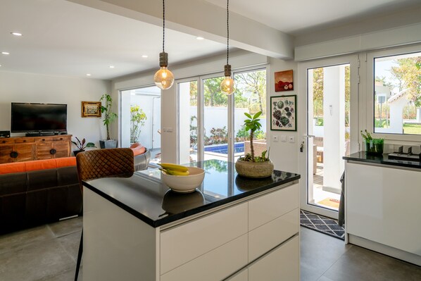 A modern kitchen with a central island, white cabinetry, and pendant lighting.