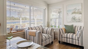 A living room with striped sofas, a glass table, and a painting on the wall. - Always Channel-On Muskegon Channel, walk to lighthouse, beach, the DECK & swim.  (Muskegon)