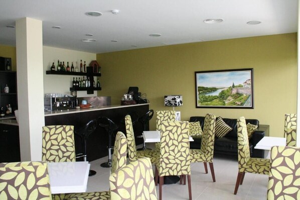 Zona de bar con estantes llenos de botellas y un cuadro de un paisaje en la pared.
