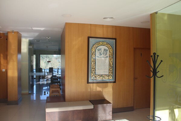 Un vestíbulo con paneles de madera, un certificado enmarcado en la pared, un perchero y una zona de estar con un banco.