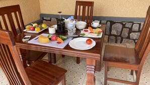 A wooden dining table with a variety of fruits, vegetables, and a coffee maker. - M Safari Club (Kigali)