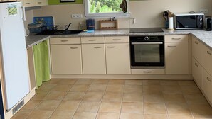 Une cuisine avec une fenêtre, des murs verts et un sol carrelé.