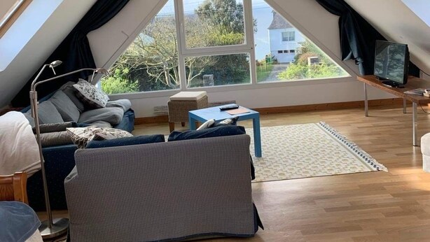 Une chambre confortable située sous les toits, avec un plafond en pente, une grande fenêtre, un lit, un canapé et une petite table.