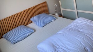 Une chambre à coucher avec un lit, deux oreillers, une lampe de chevet et une armoire aux portes en verre dépoli.