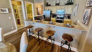 Una cocina moderna con una isla central, taburetes de bar y un comedor.