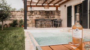 Un espace piscine agrémenté d’une pergola, de sièges d’extérieur et d’une bouteille de vin.