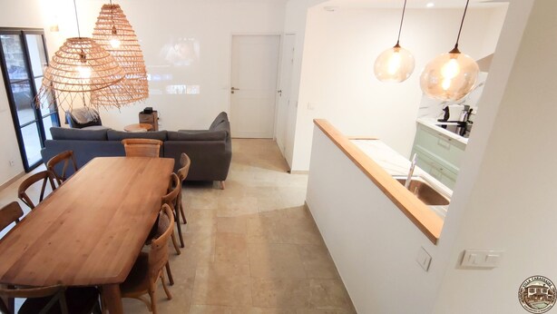 Une cuisine moderne avec un plan de travail en bois, un coin repas avec une table et des chaises en bois, et un salon avec un canapé et un téléviseur.