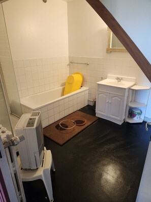 Een kleine, compacte badkamer met een bad, een witte wastafel en een toilet.