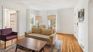 A living room with a beige sofa, a wooden coffee table, a purple armchair, and two lamps. - Vulcan View Cottage (Birmingham)
