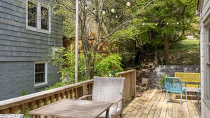 A wooden deck with a table and chairs, surrounded by greenery and a stone wall. - Vulcan View Cottage (Birmingham)