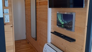 A modern room with wooden paneling, a mounted TV, a heater, and a mirror.