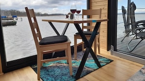 A wooden table and chairs by a large window overlooking a body of water.