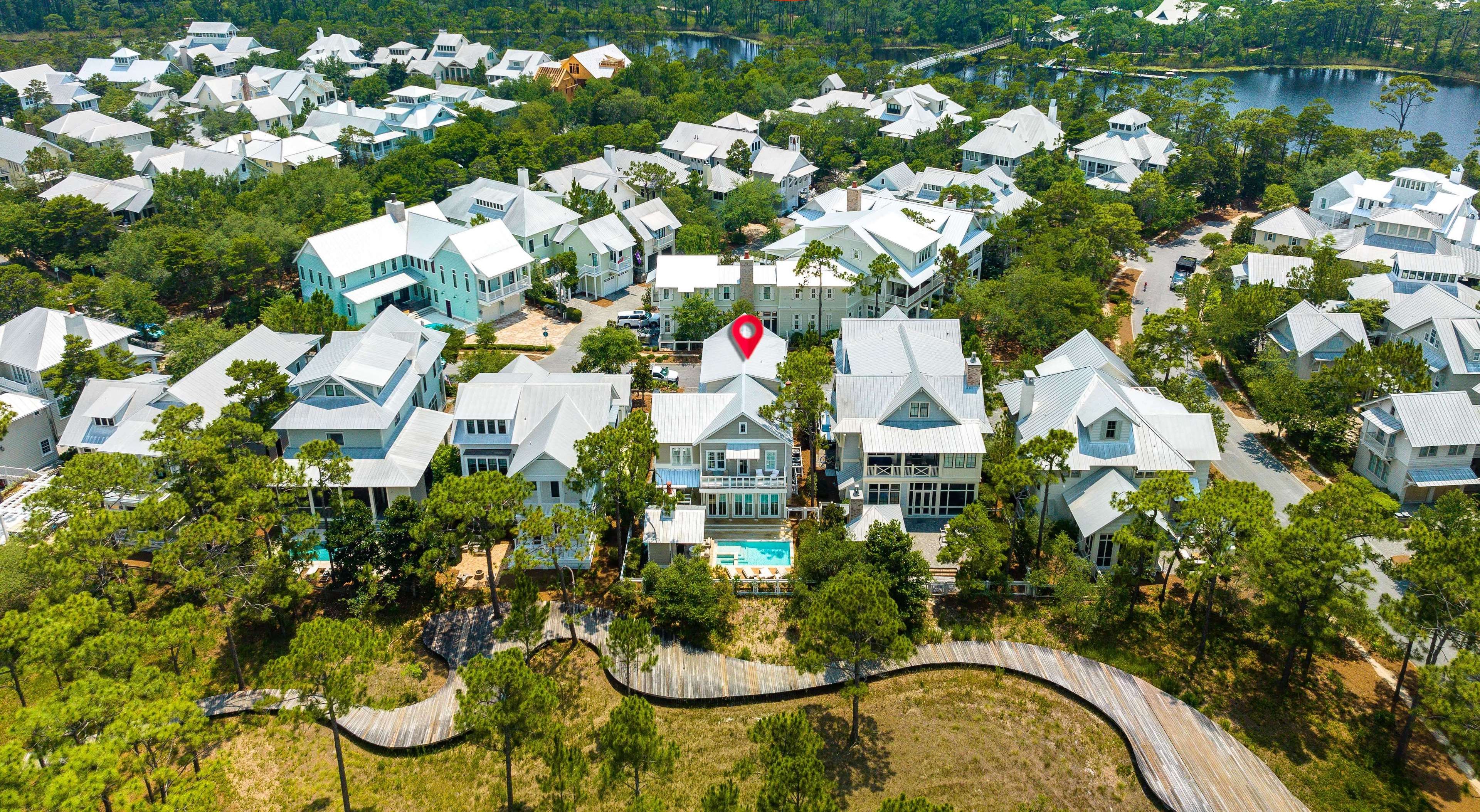 An aerial view of a residential area with houses, a beach, and a 4-minute bike ride to a beach club.