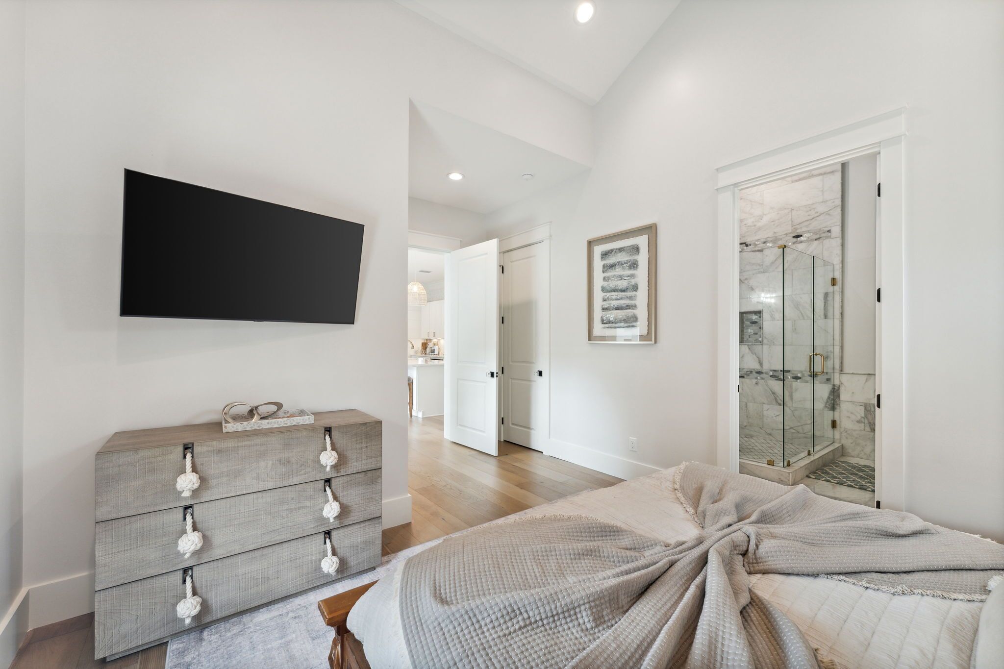 A bedroom with a bed, a dresser, a TV, and a shower.
