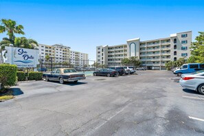 A parking lot with several cars, a sign for 'Sea Oats' hotel, and a multi-story building in the background.