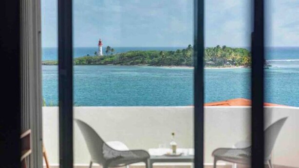 Ein Balkon mit Blick auf einen Leuchtturm auf einer kleinen Insel im Wasser.