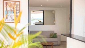 Ein modernes Wohnzimmer mit einer Couch, einem Couchtisch und einem großen Fenster mit Blick ins Freie.