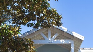A light blue house with a white porch and stairs. - HeartWind Cottage -Quaint and cozy with private pool, steps to the beach (Santa Rosa Beach)