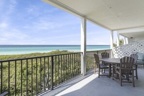 A balcony with a view of the ocean, a table with chairs, and a lattice wall.