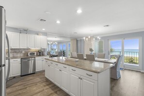 A modern kitchen with white cabinets, stainless steel appliances, and a large island.