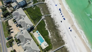 Vista aérea de una propiedad costera con piscina, acceso a la playa y varias construcciones con techos inclinados.