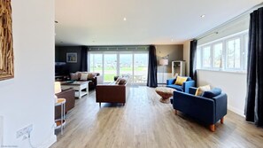 A spacious living room with a large window, a dining area, and a TV.