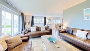 A spacious living room with leather sofas, a wooden coffee table, and a dining area in the background.