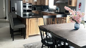 Una cocina moderna con armarios de madera, electrodomésticos de acero inoxidable y un comedor con mesa y sillas.