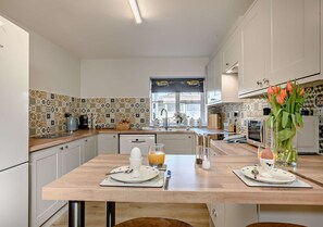 Enjoy cooking in this well-equipped kitchen with a central island, white cabinetry, and a tiled backsplash.