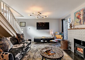 Relax in this spacious living room with a large flat-screen TV, comfortable sofa, and a fireplace.