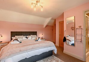 Cozy retreat with a large bed, bedside table, and full-length mirror.