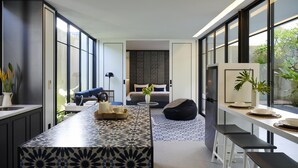 A modern kitchen with a patterned island, a dining area with stools, and a living space with a sofa and a coffee table. - Adamare Villa Umalas (Kerobokan)