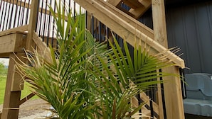 Una escalera de madera con barandales de metal que lleva a un espacio cubierto.