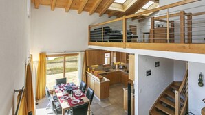 A spacious loft-style room with a dining area, kitchen, and a balcony with a view. - Martens by Interhome (Les Crosets)