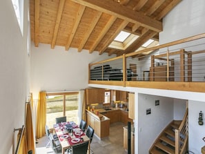A spacious loft-style room with a dining area, kitchen, and a balcony with a view.