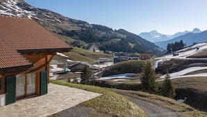 A mountain village with traditional wooden houses, a stone pathway, and a view of snow-capped mountains. - Martens by Interhome (Les Crosets)