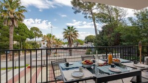 Ein Balkon mit gedecktem Tisch für das Frühstück, mit Blick auf eine Straße mit Palmen und wolkenlosem Himmel.