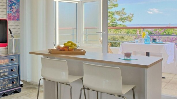 A dining area with a wooden table, two white chairs, and a view of the sea through a glass door. - Charme de Villès Martin by Interhome (Saint Nazaire)