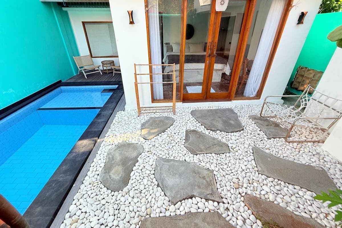 A swimming pool with a stone pathway leading to a glass door entrance.