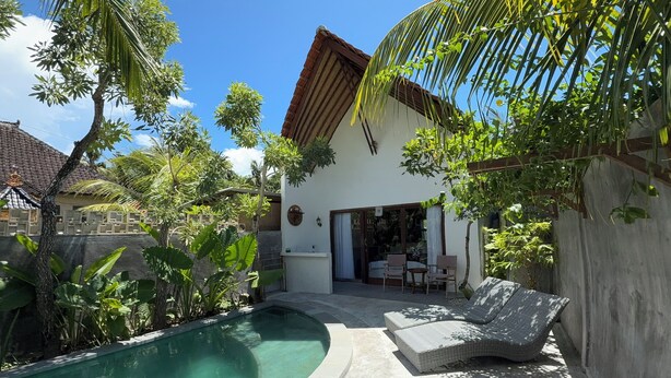A poolside area with a lounge chair, a concrete pool, and surrounding greenery. - Villa giyor (Lembongan Island)